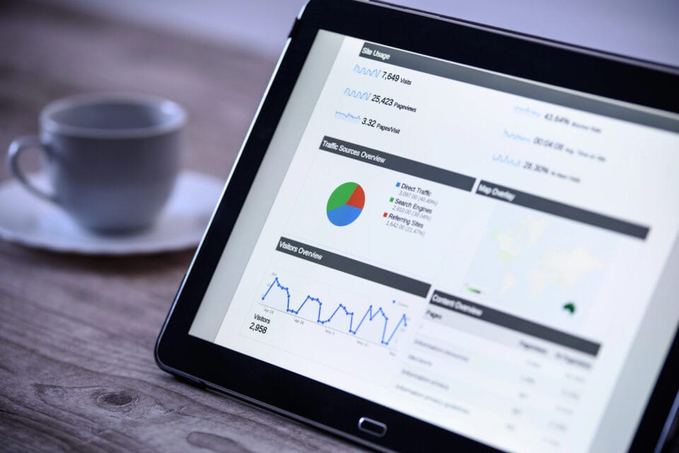 The tablet showcases website analytics with vibrant graphs and charts, including a pie chart and line graph