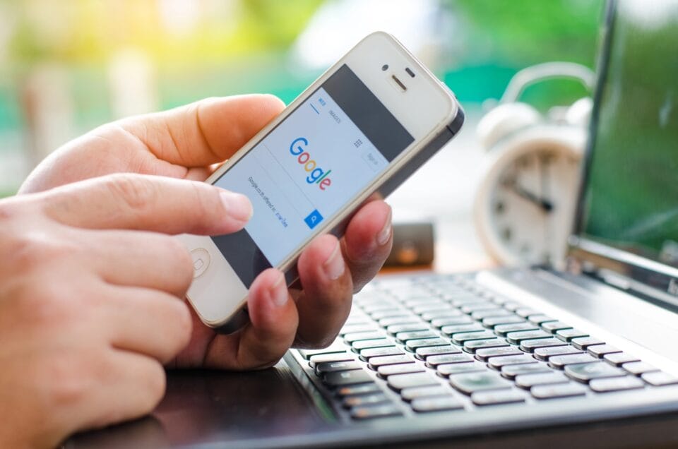 A person holding a smartphone with the Google search page open